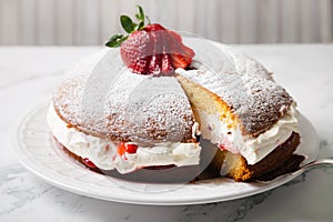 Homemade Victoria sponge cake filled with starwberries, jam and whipped cream