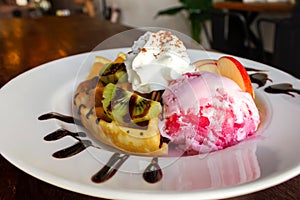 Homemade waffle served with stawberry ice cream and variety fruit. Sweet and crunchy dessert.