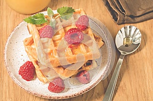 Homemade waffles with berries in plate on a old wooden background/Homemade waffles with raspberry and mint in plate on a old