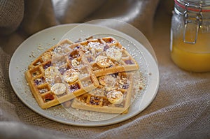 Homemade waffles with jam, honey, bananas, almonds and grated coconut.