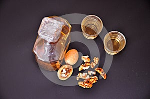 Homemade walnut liqueur, a bottle and two glasses of alcohol on a black background