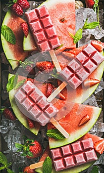 Homemade watermelon strawberry popsicles on ice with fresh fruits