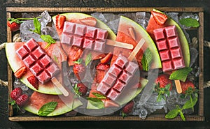 Homemade watermelon strawberry popsicles in wooden tray