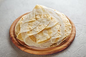 Homemade wheat flour tortilla on wooden cutting board.