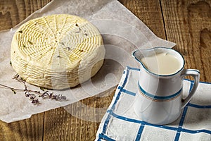 homemade wheel of cheese ang pitcher of milk on wooden table