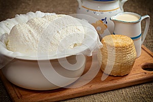 homemade wheel of cheese ang pitcher of milk on wooden table