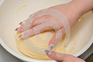 Homemade white flour dough is kneaded by female hands. Making baked goods or dumplings. Close-up, selective focus