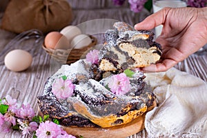 Homemade wicker cupcake with poppy seeds, flowers and icing sugar on a white wooden table. Delicious yeast pastries