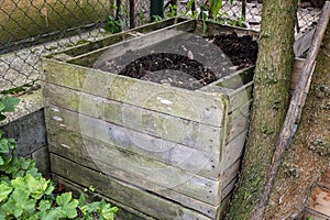 Homemade wooden compost bin in the garden. Recycling organic biodegradable material and household waste in composter. Best organic