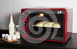 homemade yeast buns are baked in a red oven. there are ingredients: milk  eggs