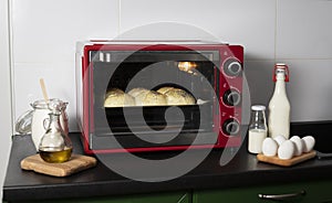 homemade yeast buns are baked in a red oven. there are ingredients: milk  eggs  flour