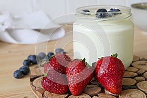 Homemade Yoghurt in a Jar with Fresh Strawberries and Blueberries on a Wooden Background