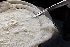 Homemade yogur being processed through cheesecloth to drain whey