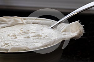 Homemade yogur being processed through cheesecloth to drain whey photo