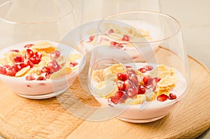 Homemade yogurt with garnet grains and flakes in glass/Homemade yogurt with garnet grains and flakes in glass on a wooden tray.