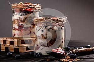Homemade yogurt parfait with granola and blueberries strawberry in glass jar on rustic wooden table. healthy breakfast
