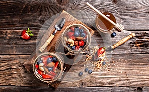 Homemade yogurt parfait with granola and blueberries strawberry in glass jar on rustic wooden table. healthy breakfast. banner,