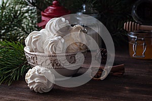 Homemade zephyr or marshmallows with pine-tree branches, cones, spices, Christmas atmosphere, wooden background