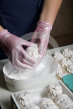 Homemade zephyr. White tray with marshmallows. A woman sprinkles marshmallows with dextrose