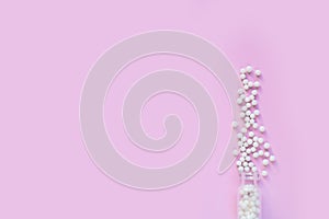 Homeopathic globules and glass bottle on pink background. Alternative Homeopathy
