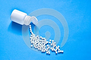 Homeopathic globules and plastic bottle on blue background. Healtcare and pills concept.  Vitamins, prebiotics, probiotics. Flat l photo