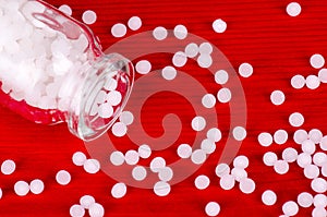 Homeopathic globules on a red wooden background