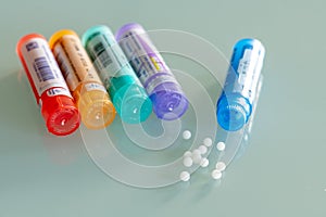 Homeopathic globules scattered around with their colored containers photo