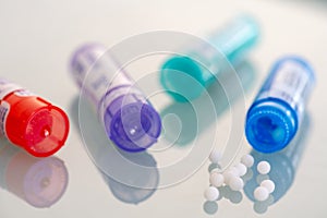 Homeopathic globules scattered around with their colored containers photo