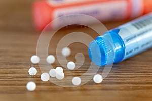 Homeopathic globules scattered around with their colored containers photo