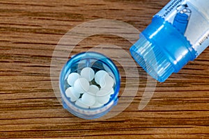 Homeopathic globules scattered around with their colored containers on a wooden table photo