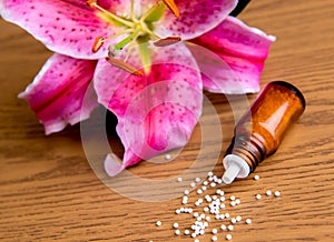 Homeopathic globules on wooden ground with lilly