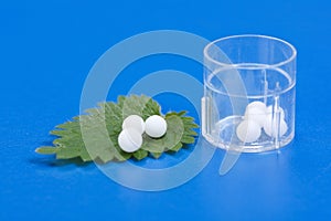 Homeopathic pills on Urtica Urens leaf photo