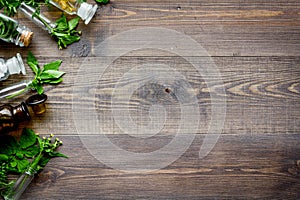 Homeopathy. Leaves of healing herbs, bottles and pills on wooden background top view copyspace