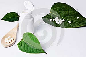 Homeopathy, naturopathy and alternative herbal medicine. Bottle with homeopathic pills on green plant leaf