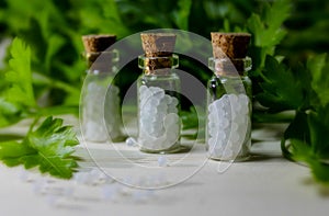 Homeopathy pills and oil in vintage bottles on wood and green background.