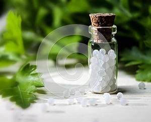 Homeopathy pills and oil in vintage bottles on wood and green background.