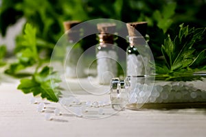 Homeopathy pills in vintage bottles on wood and green background.