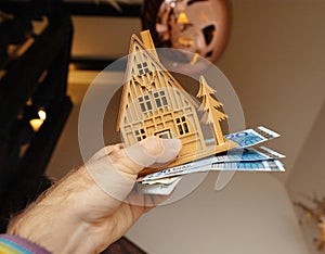Homeowner Holding Toy Wooden House with Stack of Money