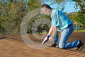 Homeowner patching roof with caulk gun protection from rain storms photo
