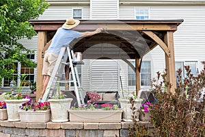 Homeowner staining a new gazebo in his backyard