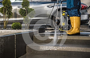 Homeowner Washing His Garden Paths and Driveway Using Pressure Washer