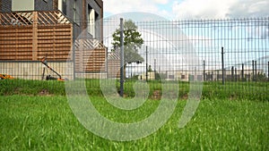 Homeowner working in garden uses lawnmower to mow a lawn