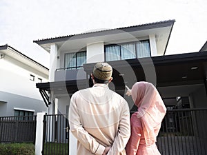Homeowners. Back view of loving muslim couple pointing and looking at their dream house