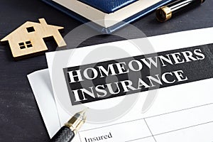 Homeowners insurance policy and model of home. photo