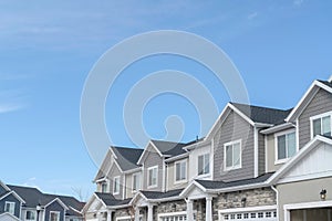 Homes with gable roofs and gray exterior walls against blue sky in the suburbs