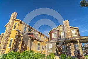 Homes with porches gable roofs and brick chimneys against vibrant blue sky