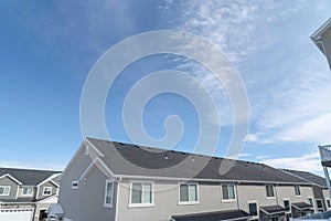 Homes in the suburbs with gray gable roof and sliding windows against blue sky