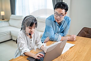Homeschool Asian little young girl learning online class from school teacher by digital remote internet meeting due to coronavirus