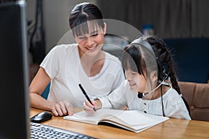 Homeschool Asian little young girl learning online class from school teacher by digital remote internet meeting due to coronavirus