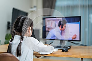 Homeschool Asian little young girl learning online class from school teacher by digital remote meeting due covid19 pandemic. Kid